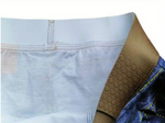 Close-up of a pair of underwear or briefs showing the light blue fabric interior, elastic waistband stitching, a tan textured waistband panel, and part of a blue denim exterior.