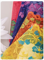 Four overlapping lace fabric panels in pink, purple, orange, and yellow, each with floral and leaf patterns, shown against a white background with a white flower prop on the left.