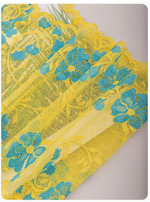 Yellow lace fabric with blue floral embroidery and scalloped edges, shown folded on a light gray background.
