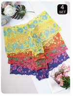 Four pairs of mens lace briefs in a stacked fan arrangement, featuring yellow with blue, orange with green, pink with purple, and dark blue floral lace. The image is styled with decorative flowers and leaves on a white surface, with a '4 SET' label in the top right corner.